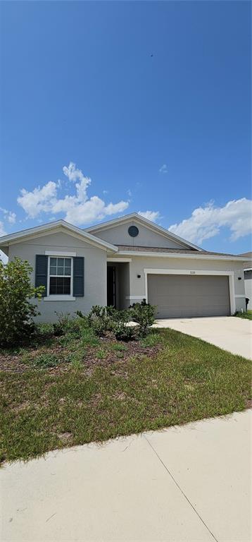 A single-story suburban house with a gray exterior, a two-car garage, and a front lawn — 1220 MATTIE POINTE BOULEVARD, AUBURNDALE, FL