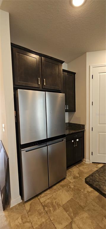 A stainless steel four-door refrigerator sits next to dark wood cabinets and granite countertops — 1220 MATTIE POINTE BOULEVARD, AUBURNDALE, FL