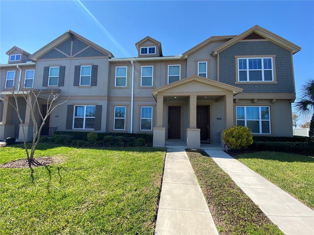 An open-concept living area with tile floors, a kitchen, and carpeted stairs — 15555 HONEYBELL DRIVE, WINTER GARDEN, FL