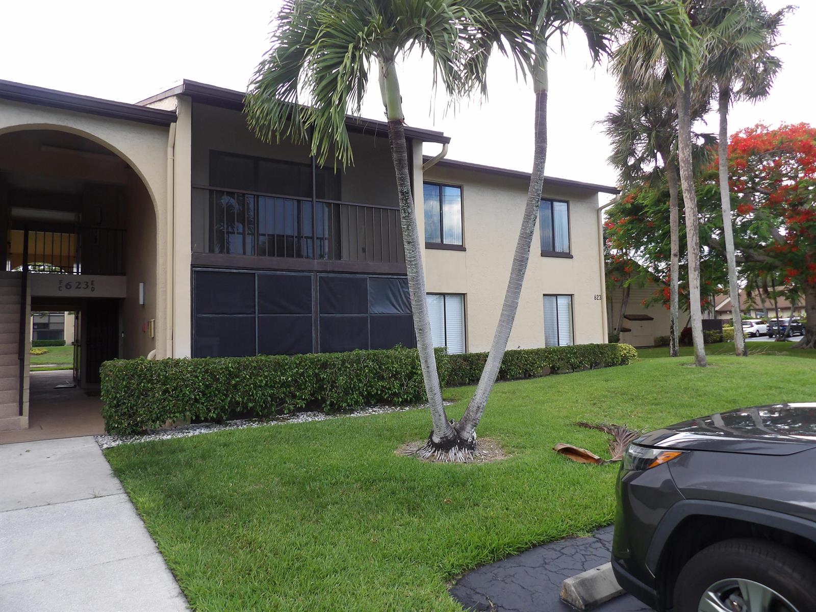 A two-story apartment building with a screened balcony, palm trees, and a manicured hedge — 623 Sea Pine Way # D2, FL 33415, FL