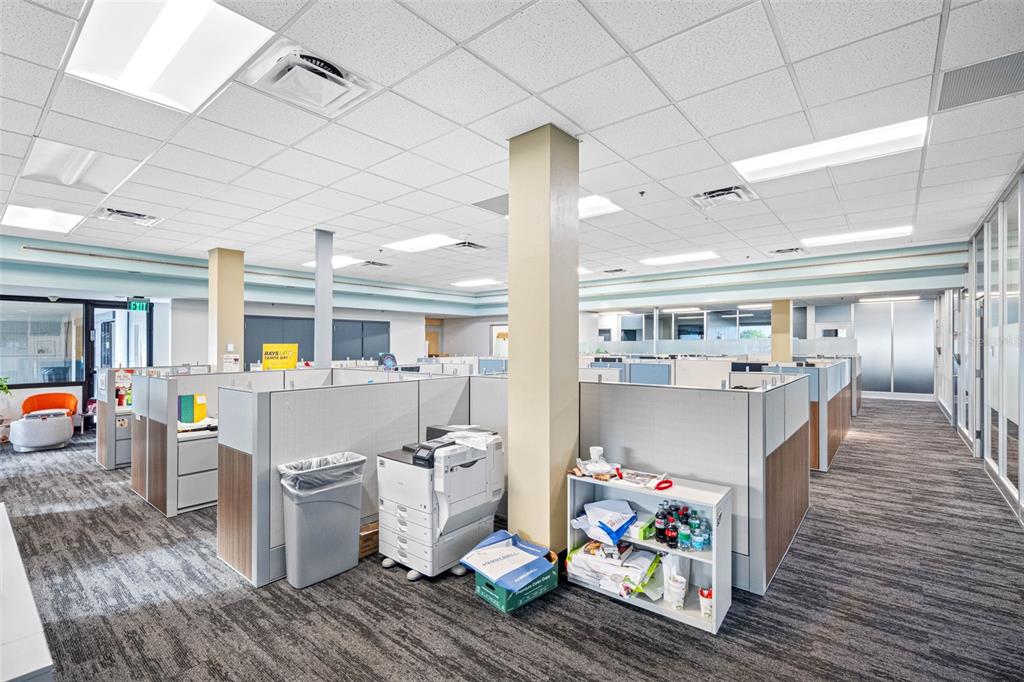 An office space with cubicles, a printer, a small shelf, and carpeted flooring — 6801 E HILLSBOROUGH AVENUE, TAMPA, FL