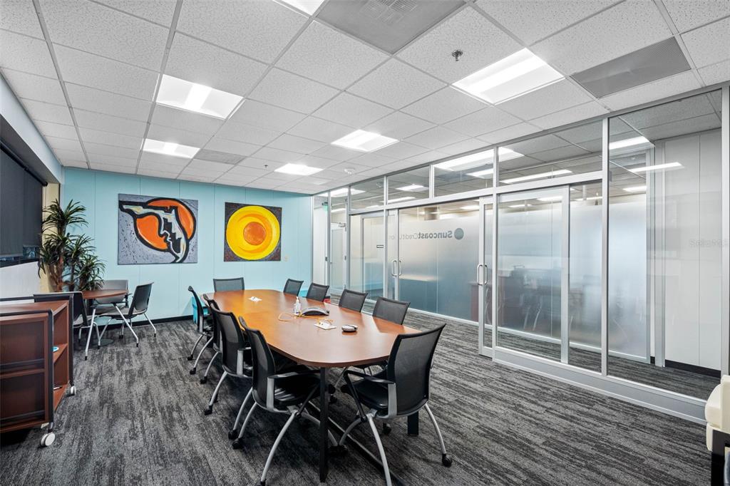A conference room features a long wooden table, black chairs, and glass-walled office partitions — 6801 E HILLSBOROUGH AVENUE, TAMPA, FL