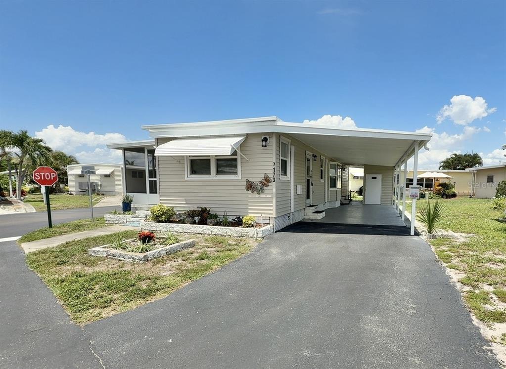 A single-story manufactured home features light siding, a carport, and a small front garden — 7173 MOUNT BRISTOL BOULEVARD NE UNIT 458, ST PETERSBURG, FL