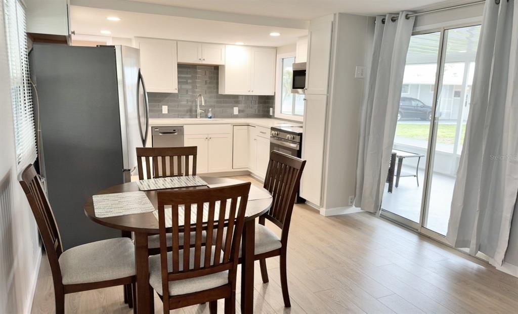 A kitchen with white cabinets, stainless steel appliances, and a dining table with four chairs — 7173 MOUNT BRISTOL BOULEVARD NE UNIT 458, ST PETERSBURG, FL