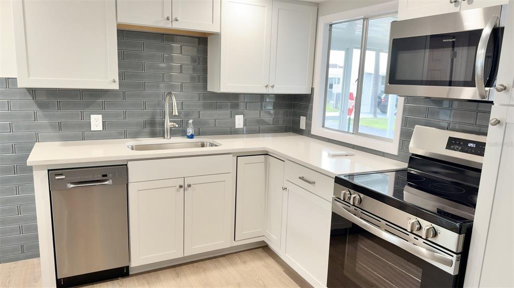 A kitchen features white cabinets, stainless steel appliances, a gray subway tile backsplash, and countertops — 7173 MOUNT BRISTOL BOULEVARD NE UNIT 458, ST PETERSBURG, FL