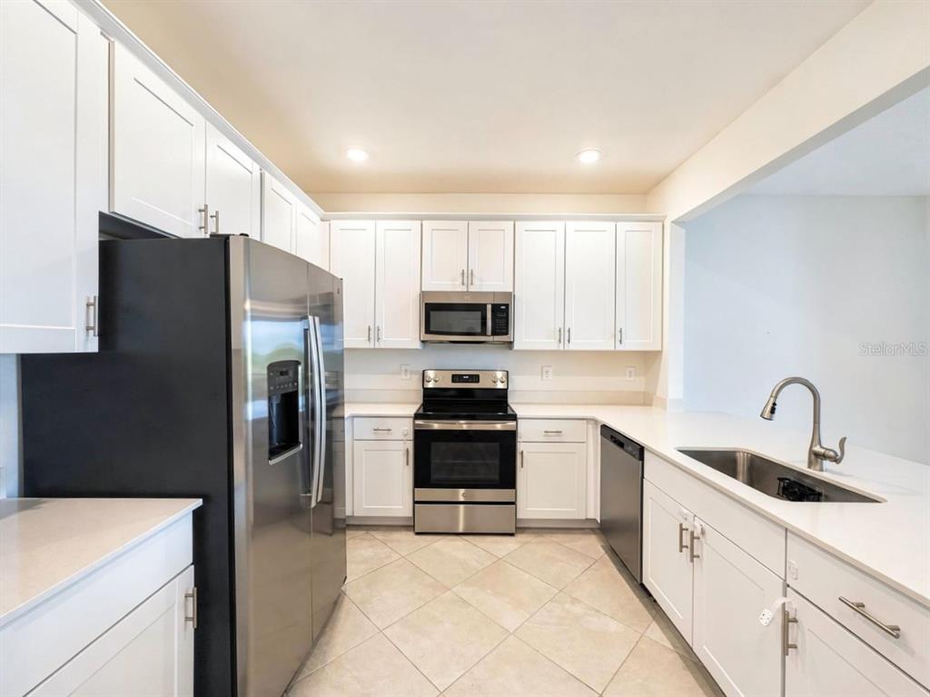 A kitchen features white cabinets, stainless steel appliances, and light-colored tile flooring — 2963 CITRUS STREET, NAPLES, FL