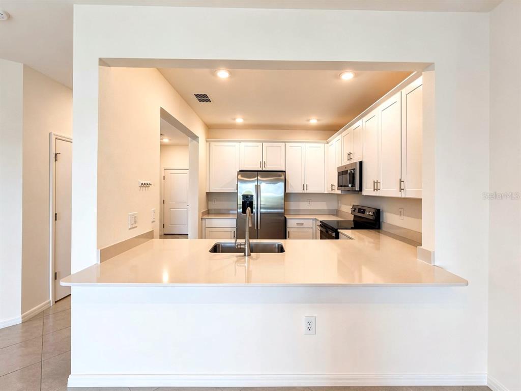 A kitchen with white cabinets, stainless steel appliances, and a quartz breakfast bar — 2963 CITRUS STREET, NAPLES, FL