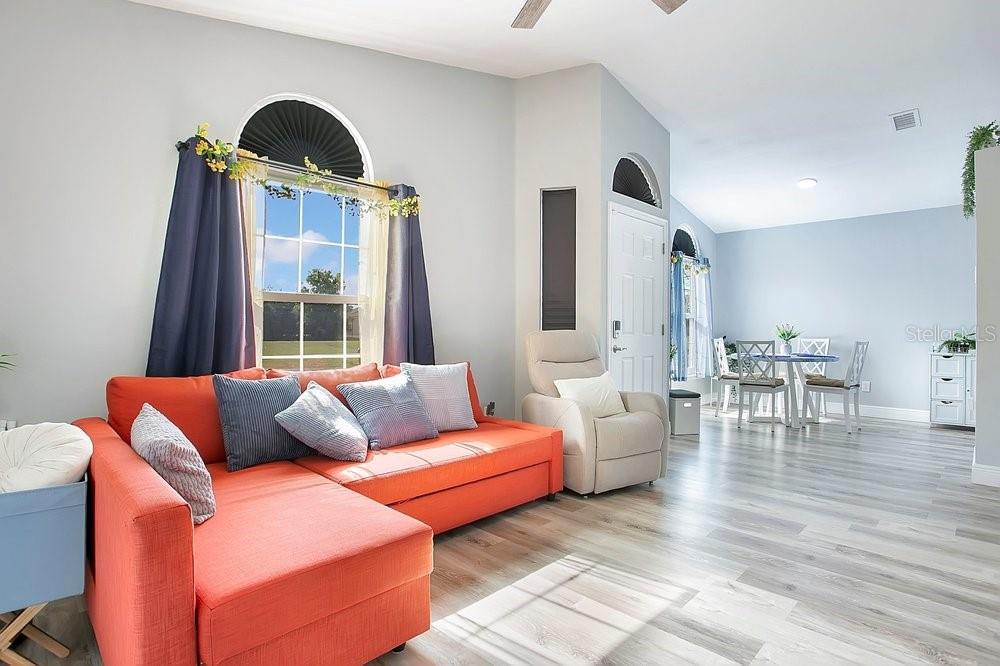 A living room with an orange sectional, a recliner, and a dining area beyond — 130 DEER SONG DRIVE, WINTER SPRINGS, FL