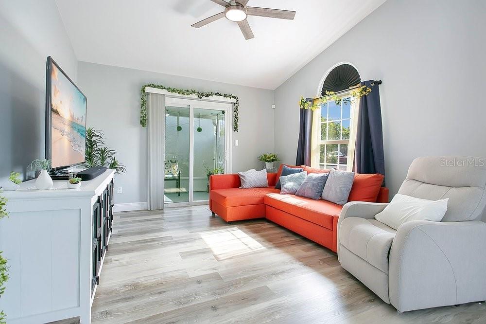 A living room features light wood floors, an orange sectional sofa, and a white recliner — 130 DEER SONG DRIVE, WINTER SPRINGS, FL