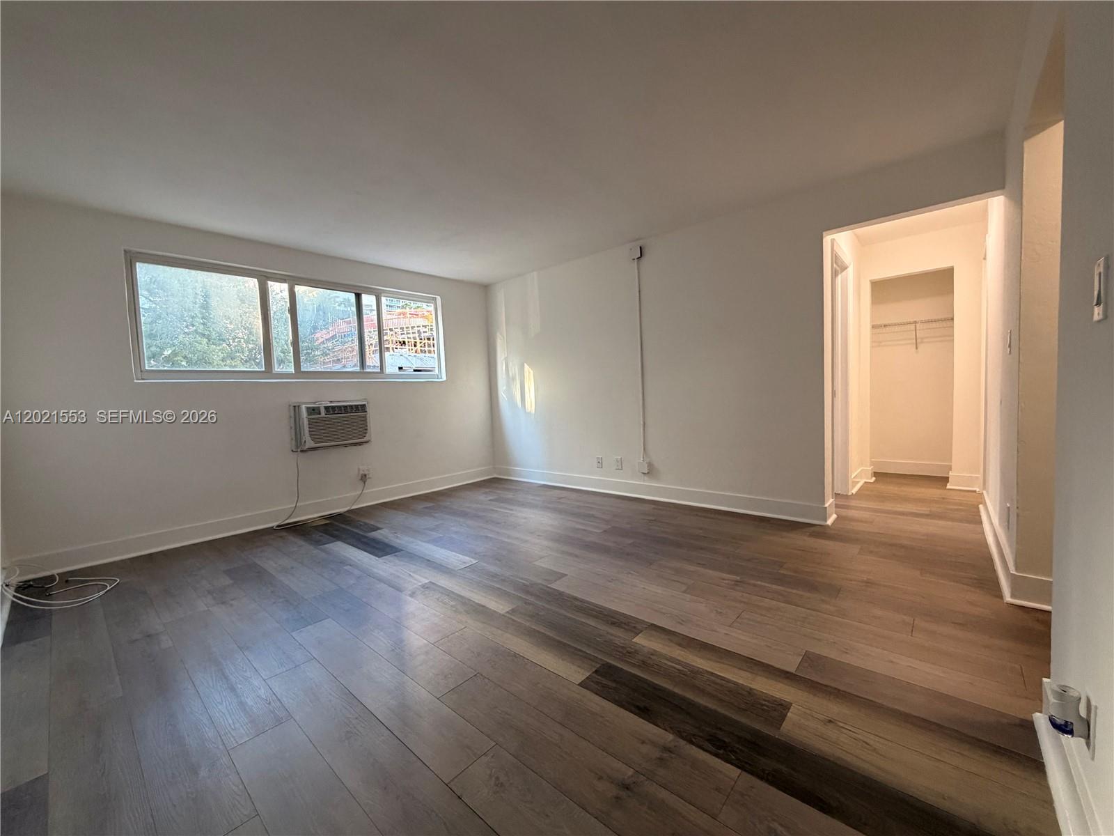 An empty room features wood-look flooring, a window air conditioning unit, and an open closet — 143 SW 9th St # 106, Miami FL 33130, MIAMI, FL