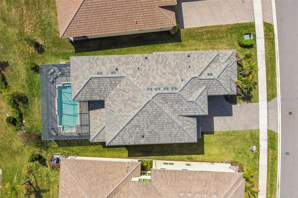 An aerial view shows a house with a gray tiled roof and a screened-in pool — 3416 ACACIA BAY AVENUE, WESLEY CHAPEL, FL