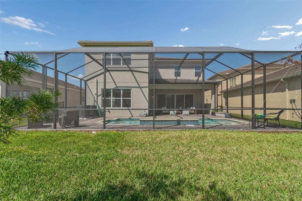 A two-story house with a screened-in pool and patio area viewed from the backyard — 3416 ACACIA BAY AVENUE, WESLEY CHAPEL, FL