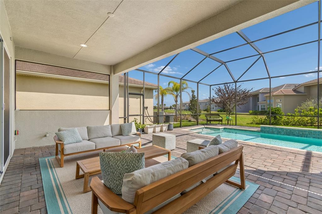 A covered patio with outdoor furniture overlooks a screened-in swimming pool and backyard — 3416 ACACIA BAY AVENUE, WESLEY CHAPEL, FL