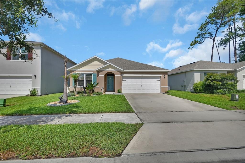 A single-story suburban house with a tan exterior, a two-car garage, and a front lawn — 531 EMILY GLEN STREET, DELAND, FL