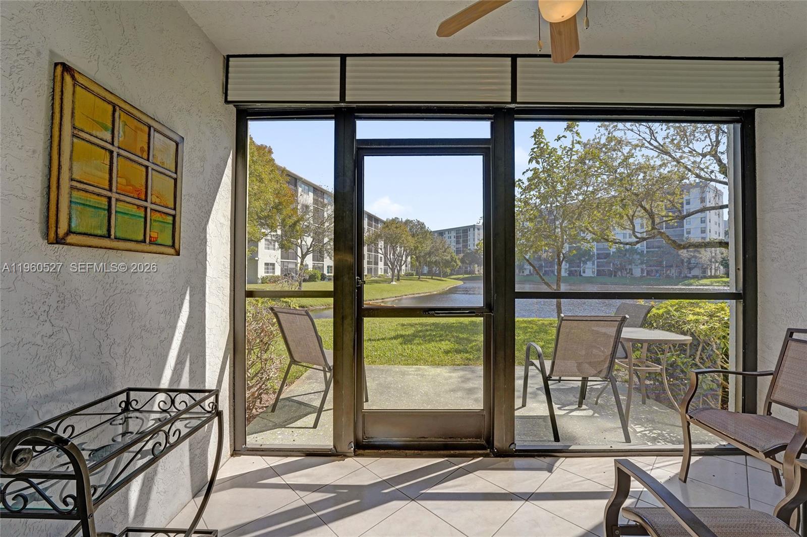 A screened-in patio features tile flooring, outdoor furniture, and a view of a lake — 2228 N Cypress Bend Dr # 103, Pompano Beach FL 33069, POMPANO BEACH, FL