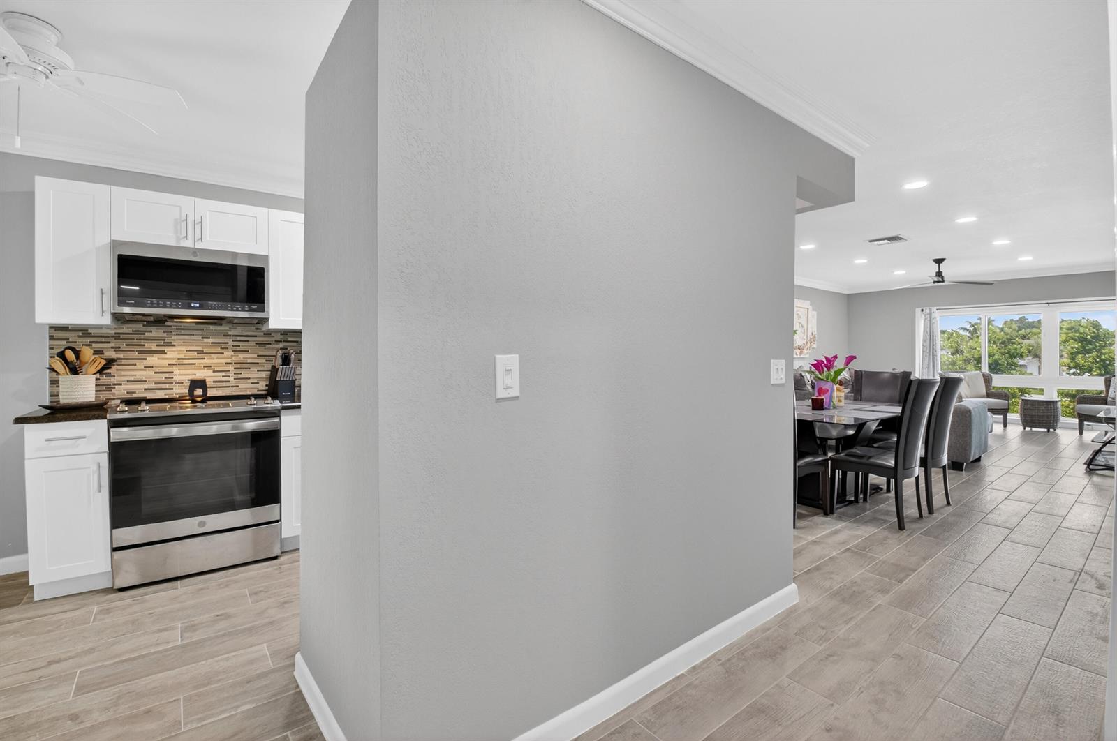 A kitchen with white cabinets and stainless steel appliances opens to a dining and living area — 13767 Flora Place # F, Delray Beach FL 33484, DELRAY BEACH, FL