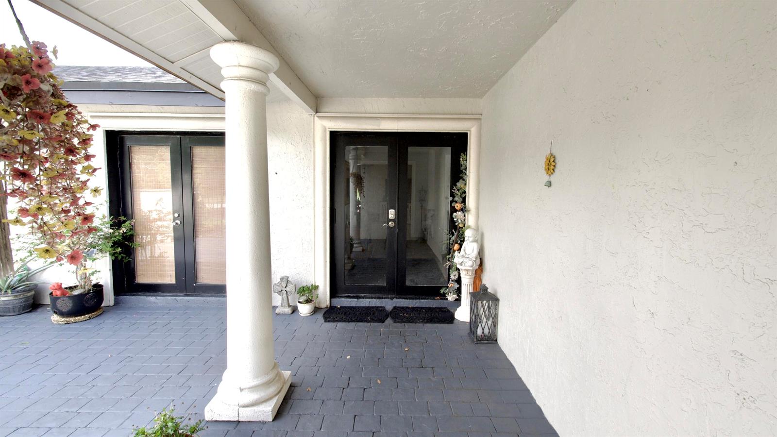 A covered patio features a white column, dark double doors, and a stone-tiled floor — 5191 SW 109th Avenue, Davie FL 33328, DAVIE, FL