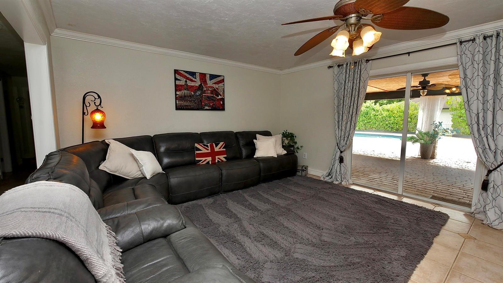 A living room features a dark leather sectional, a grey shag rug, and sliding glass doors — 5191 SW 109th Avenue, Davie FL 33328, DAVIE, FL