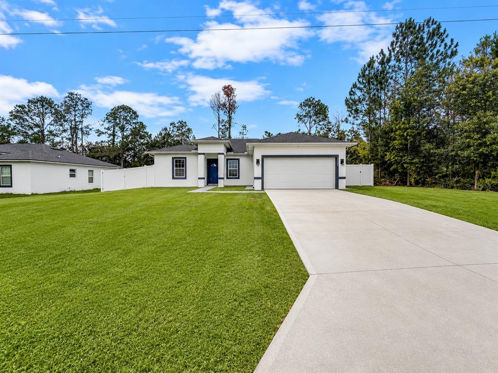A white single-story house with a blue front door and a two-car garage — 13340 SW 49TH AVENUE, OCALA, FL