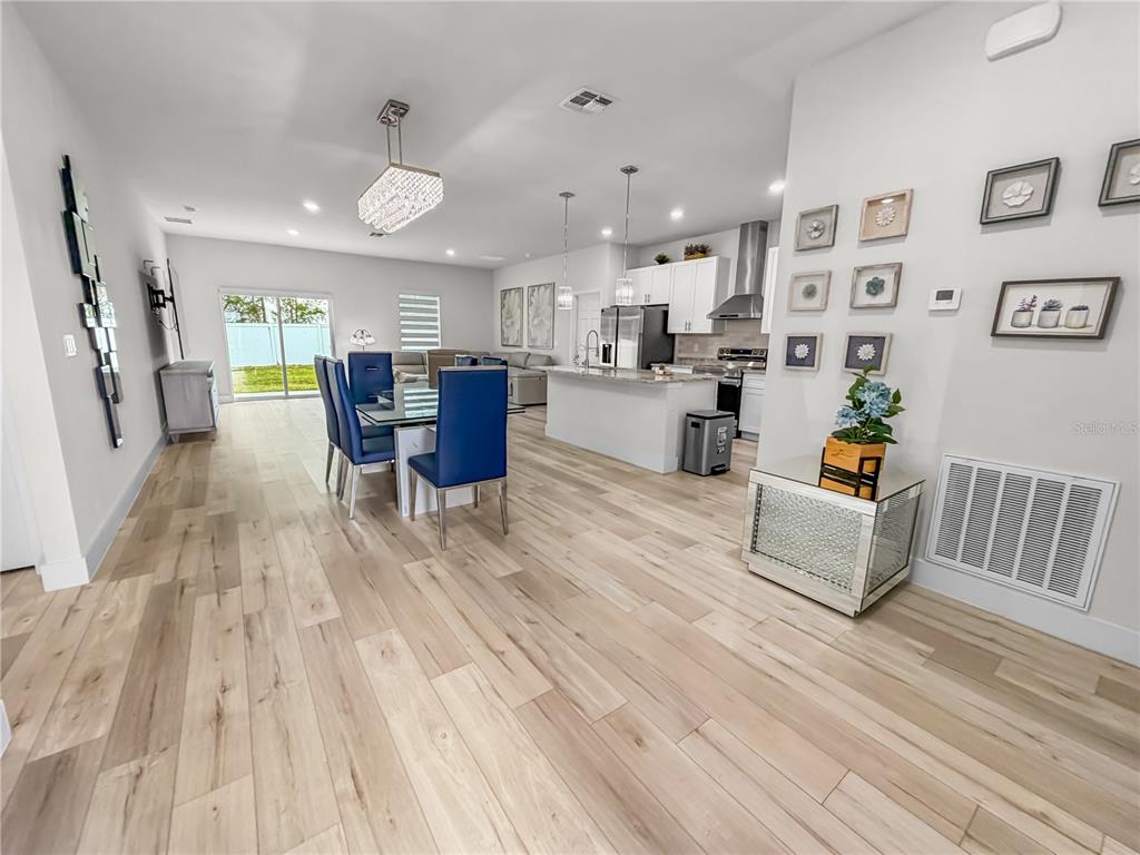 An open-concept kitchen and dining area features light wood flooring and blue upholstered chairs — 13340 SW 49TH AVENUE, OCALA, FL