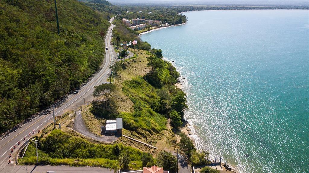 An aerial view shows a coastal road winding along a hillside next to the ocean — BO. CAGUABO, ANASCO, PR