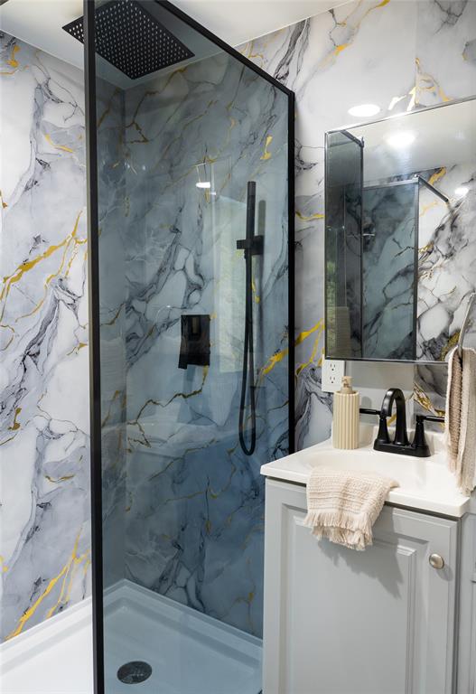 A bathroom features a walk-in shower with marble-patterned walls, a black shower head, and vanity — BO. CAGUABO, ANASCO, PR