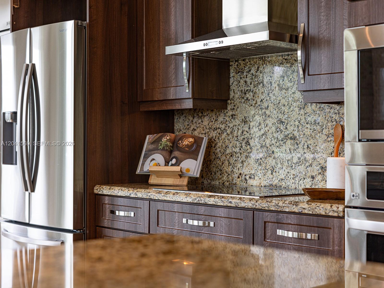 A kitchen features dark wood cabinets, granite countertops, stainless steel appliances, and a tiled backsplash — 2645 S Bayshore Dr # 304, Miami FL 33133, MIAMI, FL