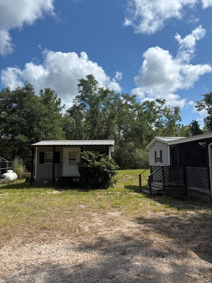 Two small, light-colored cabins with metal roofs sit on a grassy, sandy lot — 423 NW Bright Lake Court, FL 32096, FL