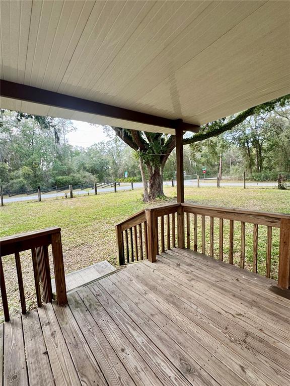 A wooden deck with railings overlooks a grassy yard and a large tree — 1981 CR 615B, BUSHNELL, FL