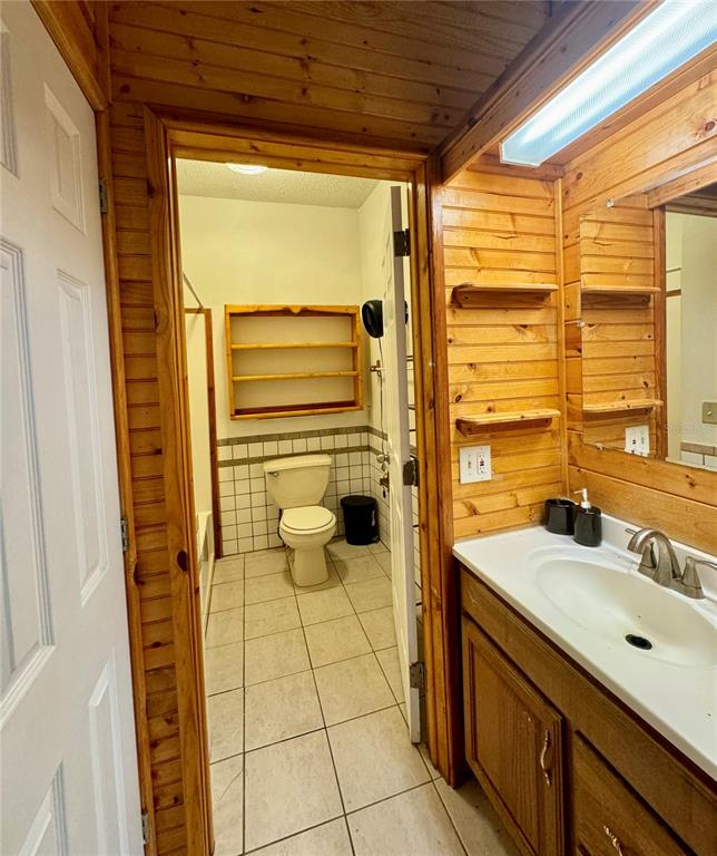 A bathroom features wood-paneled walls, a vanity with a sink, and a separate toilet area — 1981 CR 615B, BUSHNELL, FL