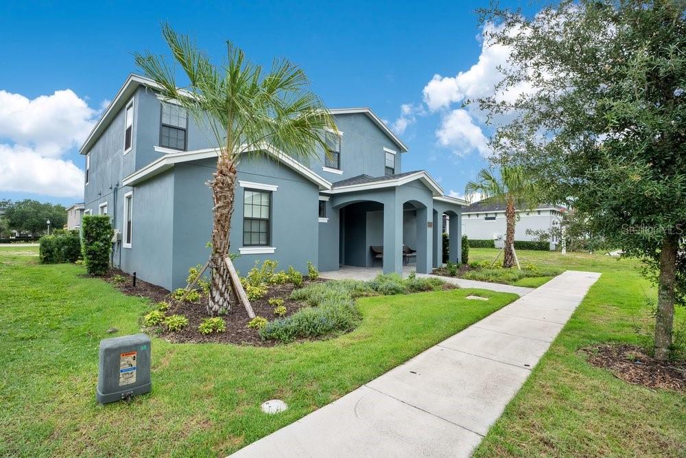 A two-story blue house with a covered entryway and a concrete sidewalk in the foreground — 7417 SPARKLING COURT, REUNION, FL