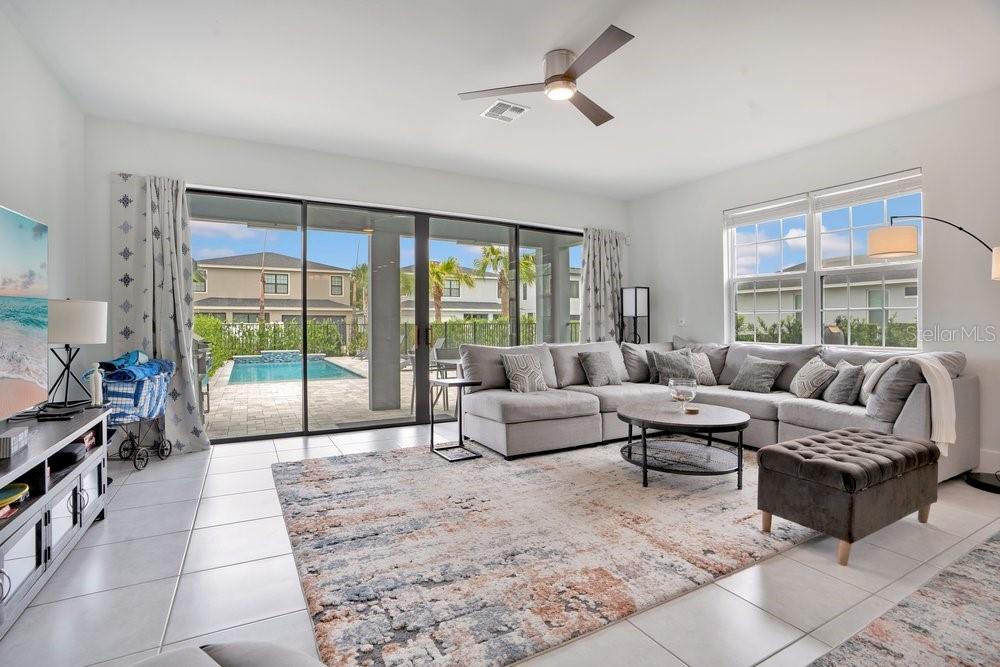 A living room with a large sectional sofa, area rug, and sliding doors to a pool — 7417 SPARKLING COURT, REUNION, FL