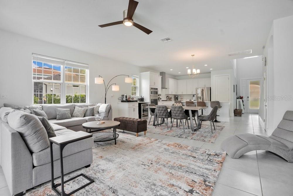 An open-concept living and dining area features light gray furniture, tile flooring, and white cabinetry — 7417 SPARKLING COURT, REUNION, FL