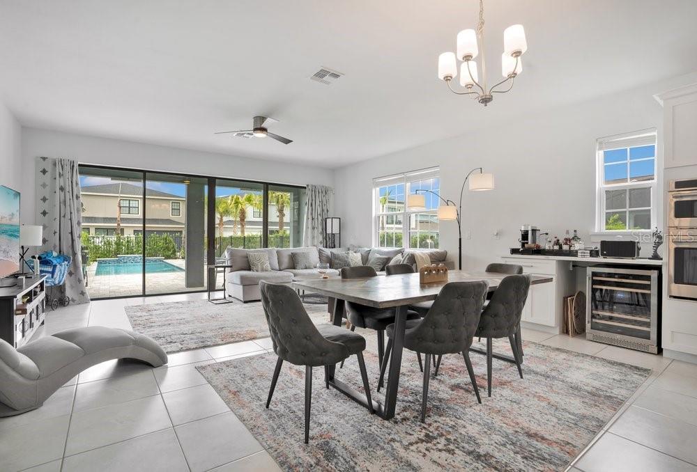 A bright open-concept living and dining area features tile floors, a pool view, and furniture — 7417 SPARKLING COURT, REUNION, FL