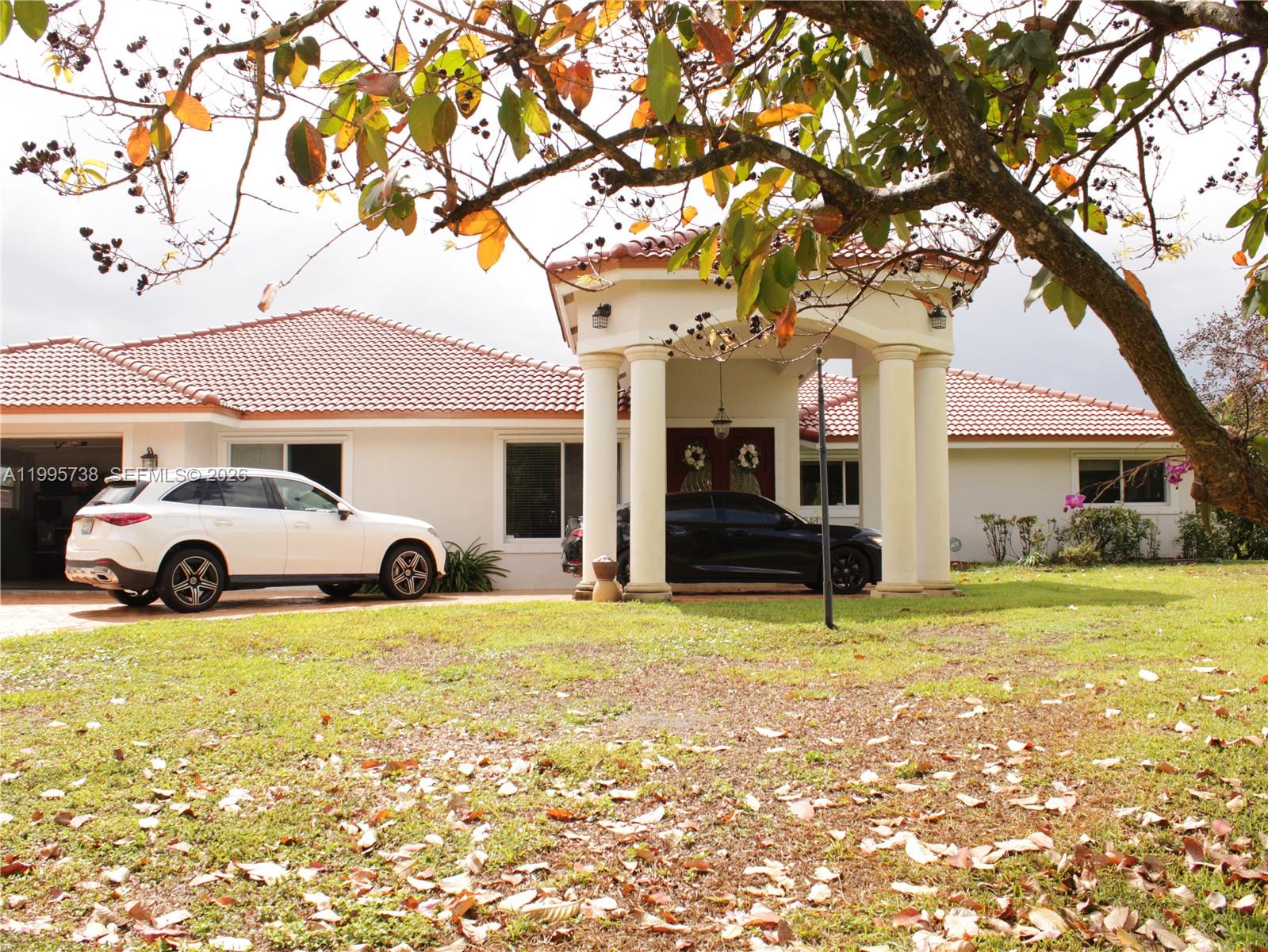 A single-story house with a tiled roof and a columned entryway sits behind a lawn — 4931 SW 167th Ave, Southwest Ranches FL 33331, SOUTHWEST RANCHES, FL