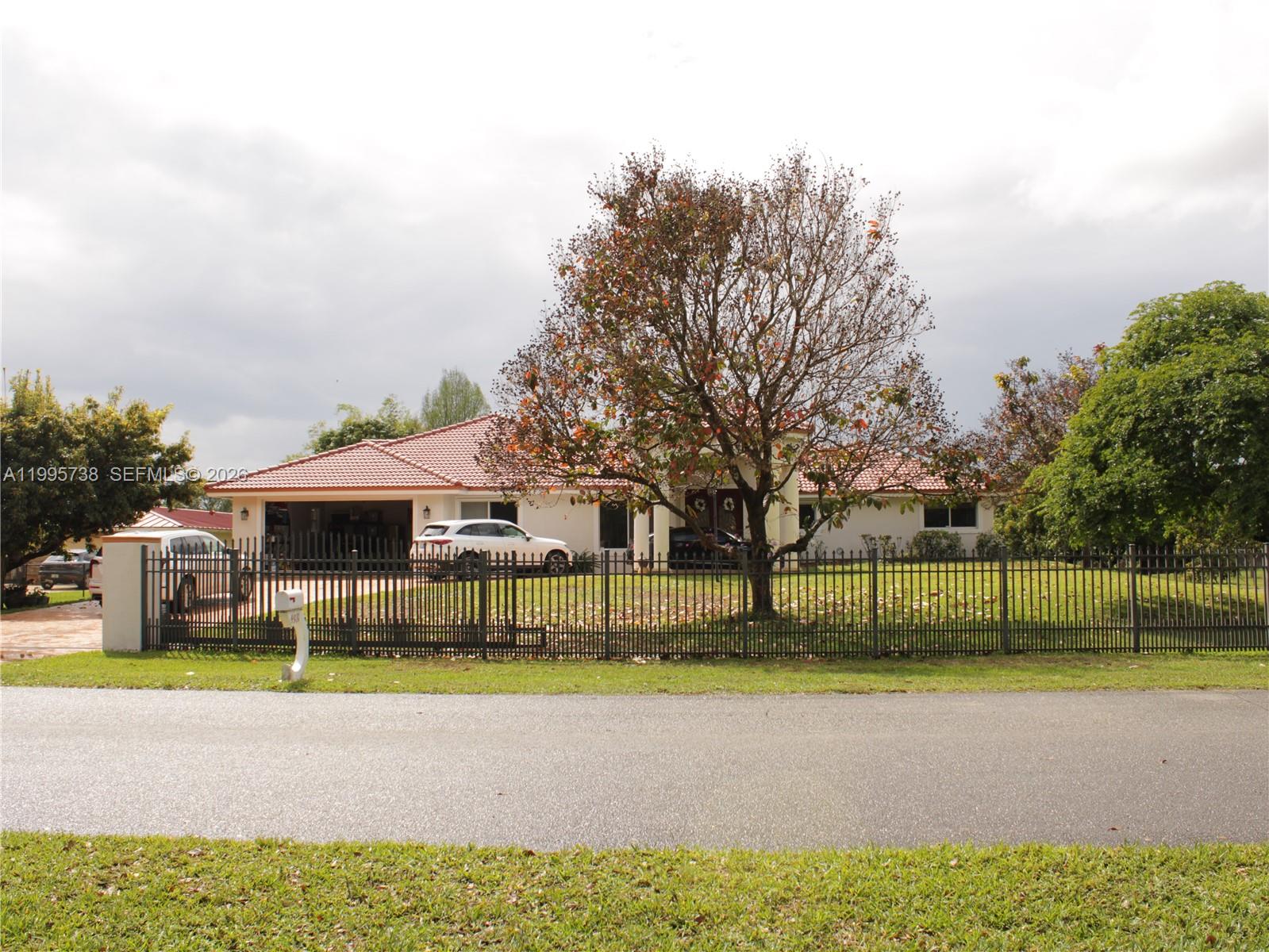 A single-story house with a tiled roof and a large tree behind a metal fence — 4931 SW 167th Ave, Southwest Ranches FL 33331, SOUTHWEST RANCHES, FL