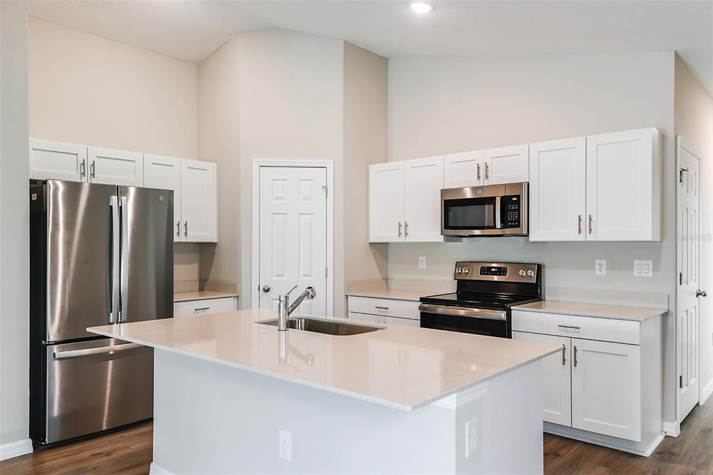 A kitchen features white cabinets, stainless steel appliances, a center island, and light-colored countertops — 1751 VANILLA STREET, HAINES CITY, FL