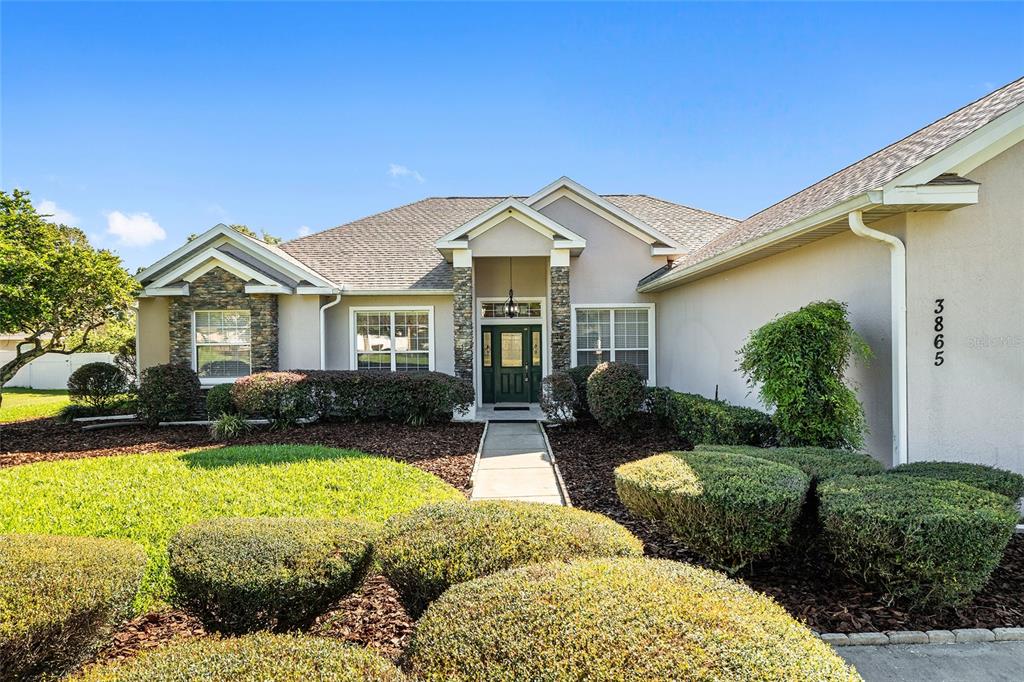 A single-story house with a stone-accented facade, a dark green front door, and manicured landscaping — 3865 SE 52ND AVENUE, OCALA, FL