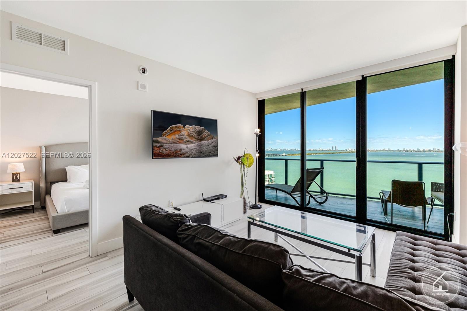 A living room with a dark sofa, glass coffee table, and balcony overlooking the ocean — 460 NE 28th St # 1707, Miami FL 33137, MIAMI, FL