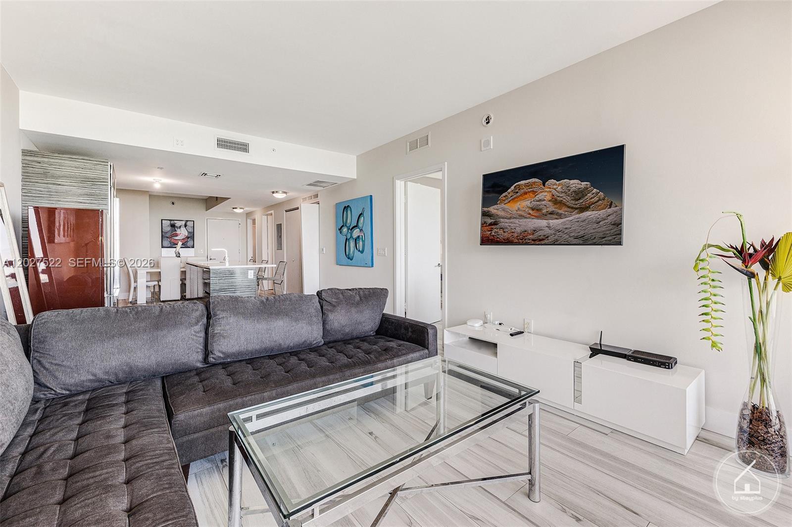 A living room features a grey sectional sofa, glass coffee table, and wall-mounted television — 460 NE 28th St # 1707, Miami FL 33137, MIAMI, FL