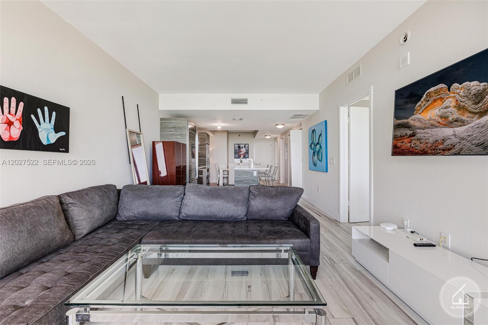 A living room features a grey sectional sofa, glass coffee table, and wall-mounted television — 460 NE 28th St # 1707, Miami FL 33137, MIAMI, FL