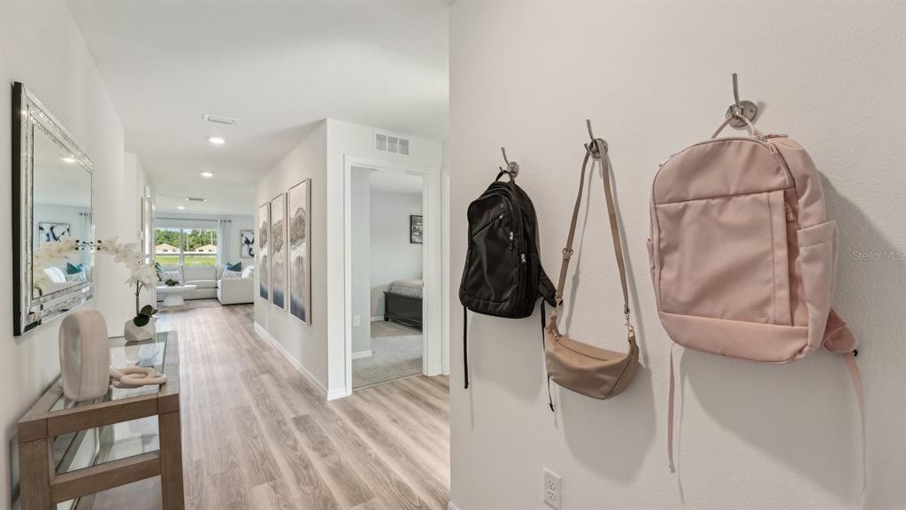 A hallway features light wood-look flooring, a console table with a mirror, and wall-mounted hooks — 11019 NW 167TH TERRACE, ALACHUA, FL