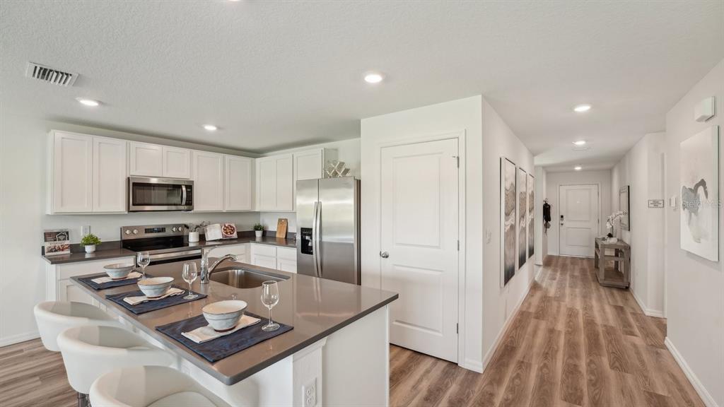 A modern kitchen features white cabinetry, stainless steel appliances, and a large quartz-topped island — 11019 NW 167TH TERRACE, ALACHUA, FL