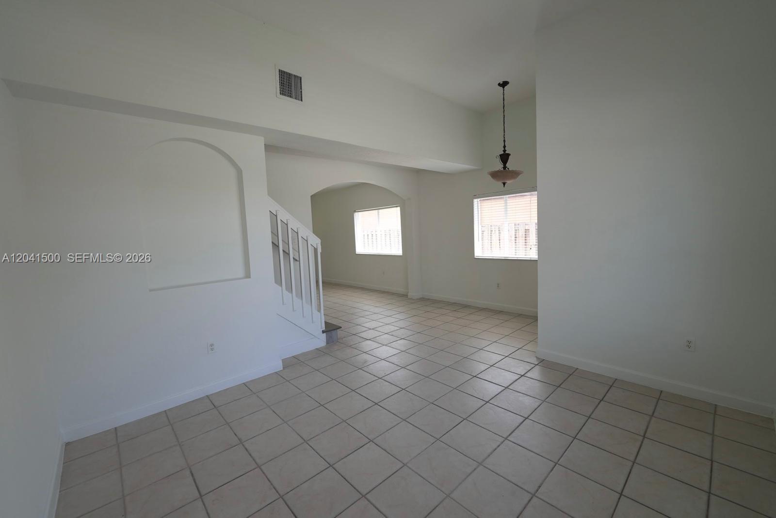 An interior view shows a tiled living area with a staircase, arched wall niche, and windows — 8836 SW 221 TERR, Miami FL 33190, MIAMI, FL