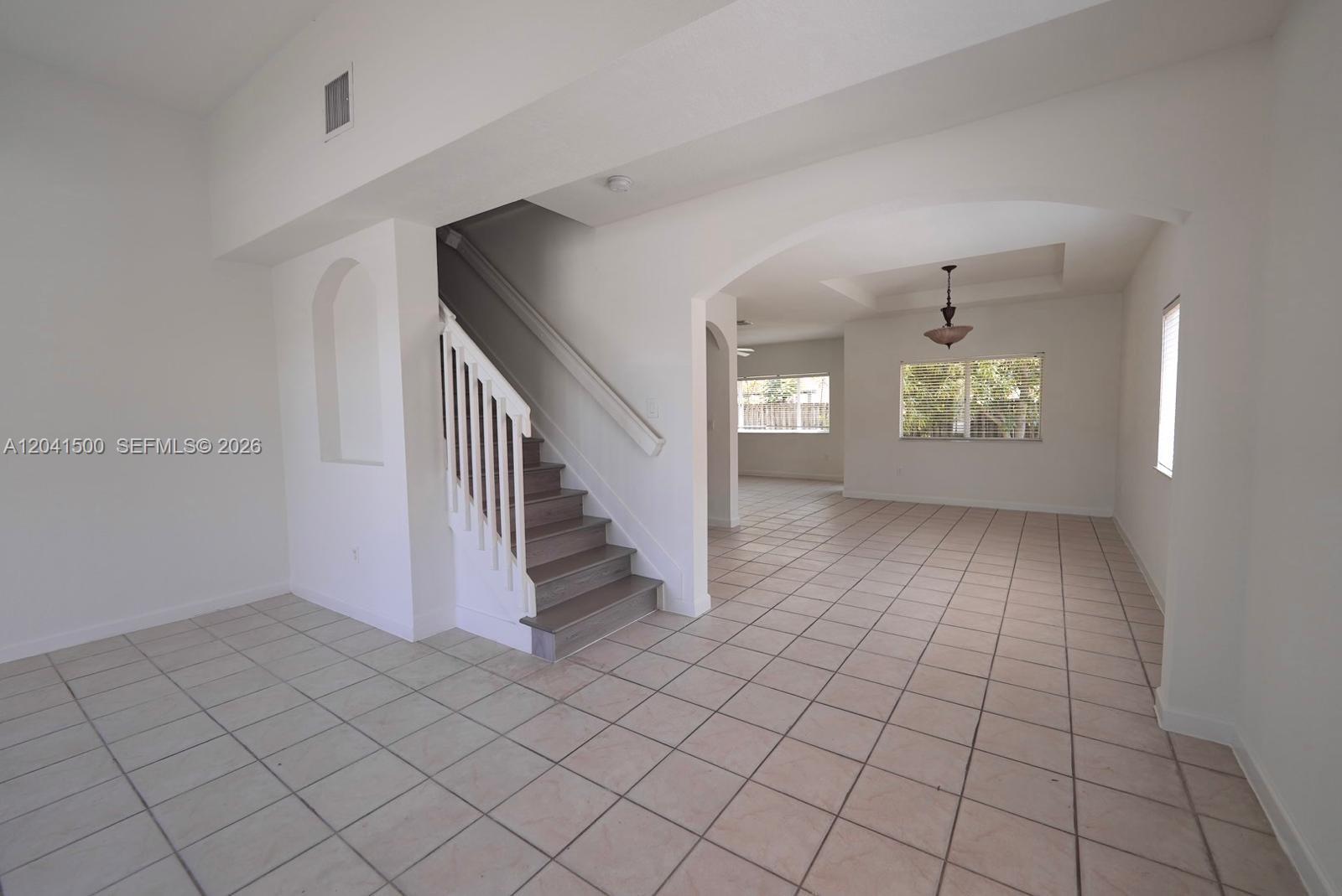 An interior view shows a tiled living area with a staircase and arched architectural details — 8836 SW 221 TERR, Miami FL 33190, MIAMI, FL