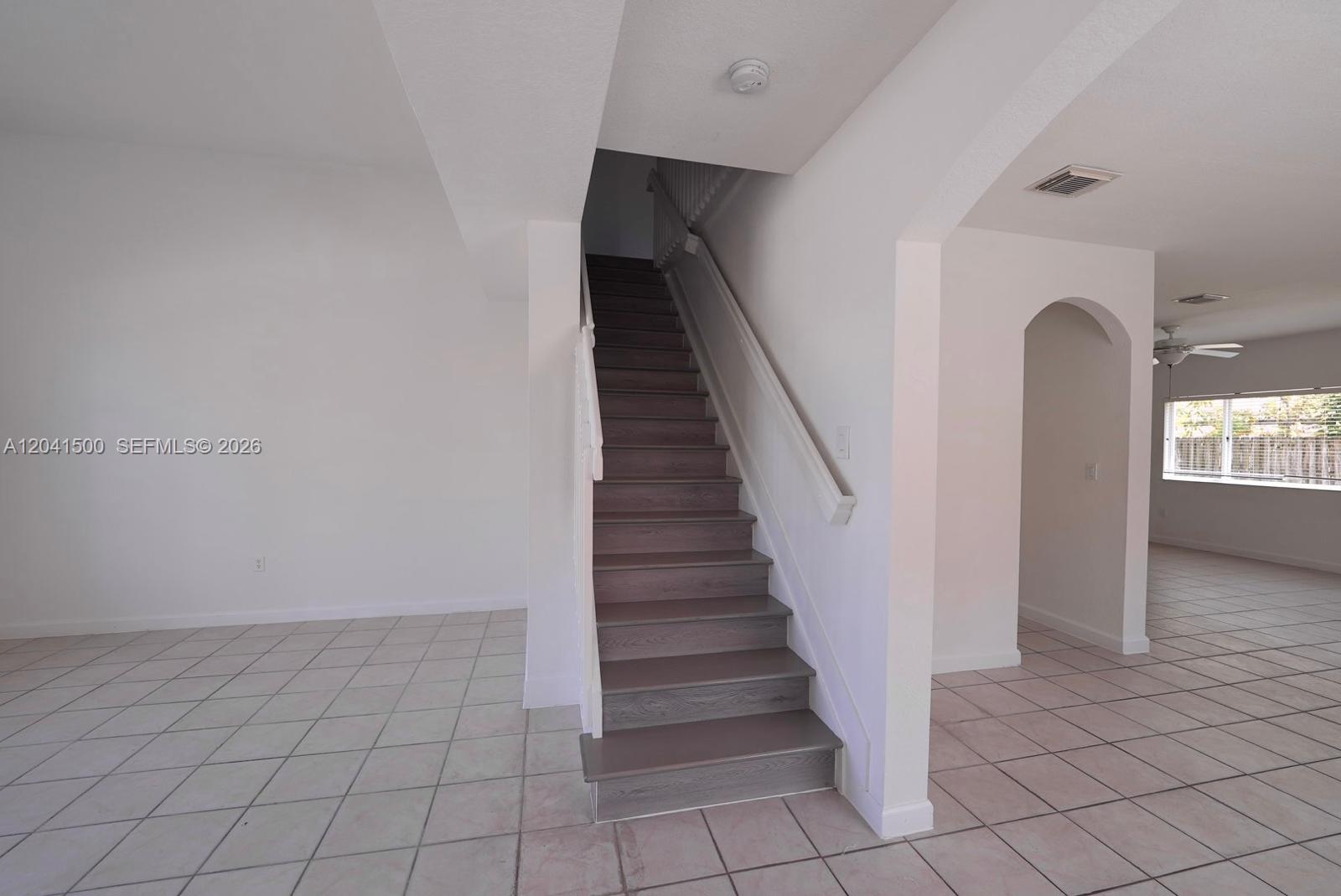 A staircase with dark wood treads leads upward between white walls and tiled floors — 8836 SW 221 TERR, Miami FL 33190, MIAMI, FL