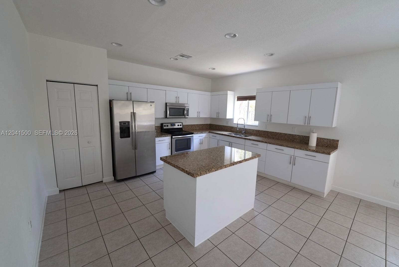 A kitchen features white cabinets, granite countertops, stainless steel appliances, and a central island — 8836 SW 221 TERR, Miami FL 33190, MIAMI, FL