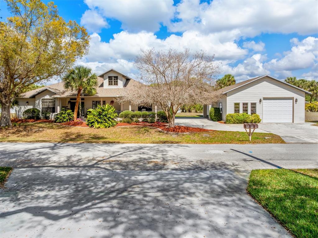 A single-story house with a detached garage, a large front yard, and mature trees — 18412 MEYER AVENUE, PORT CHARLOTTE, FL