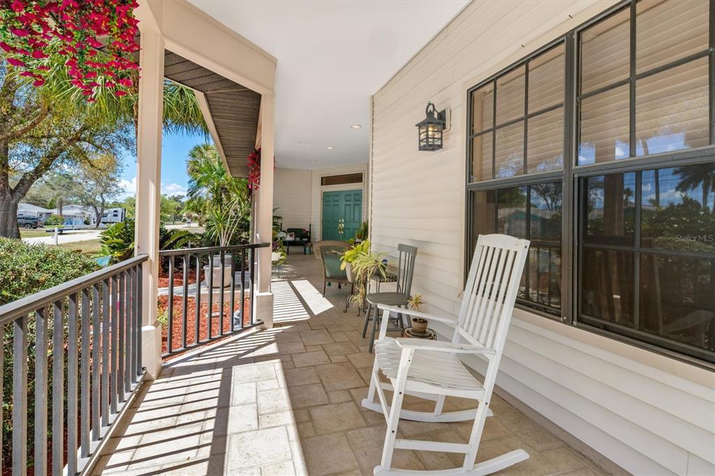 A covered porch features a white rocking chair, tiled flooring, and a view of the yard — 18412 MEYER AVENUE, PORT CHARLOTTE, FL