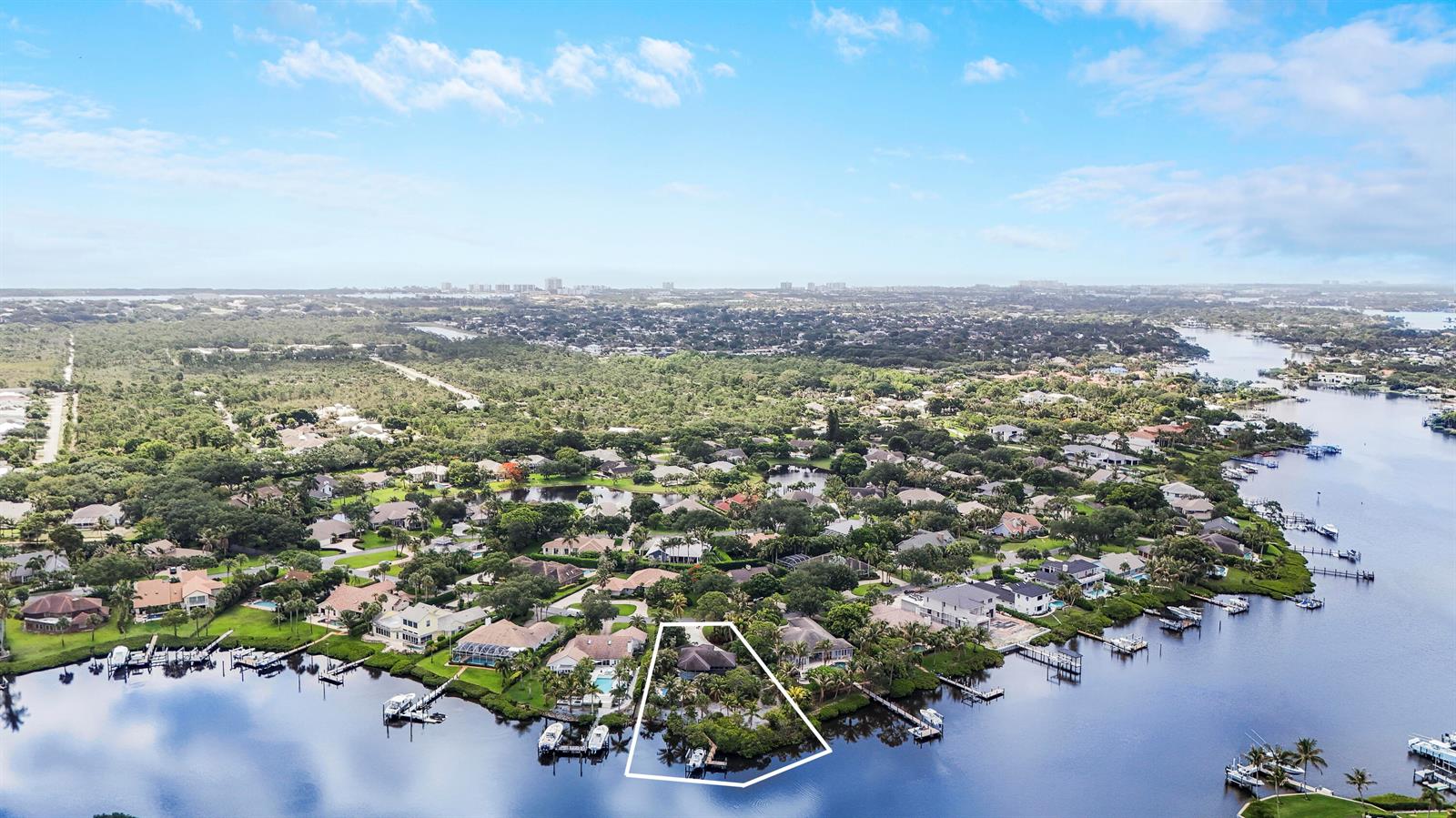 An aerial view shows a waterfront house with a private dock and surrounding vegetation — 18791 SE River Ridge Road, Jupiter FL 33469, JUPITER, FL